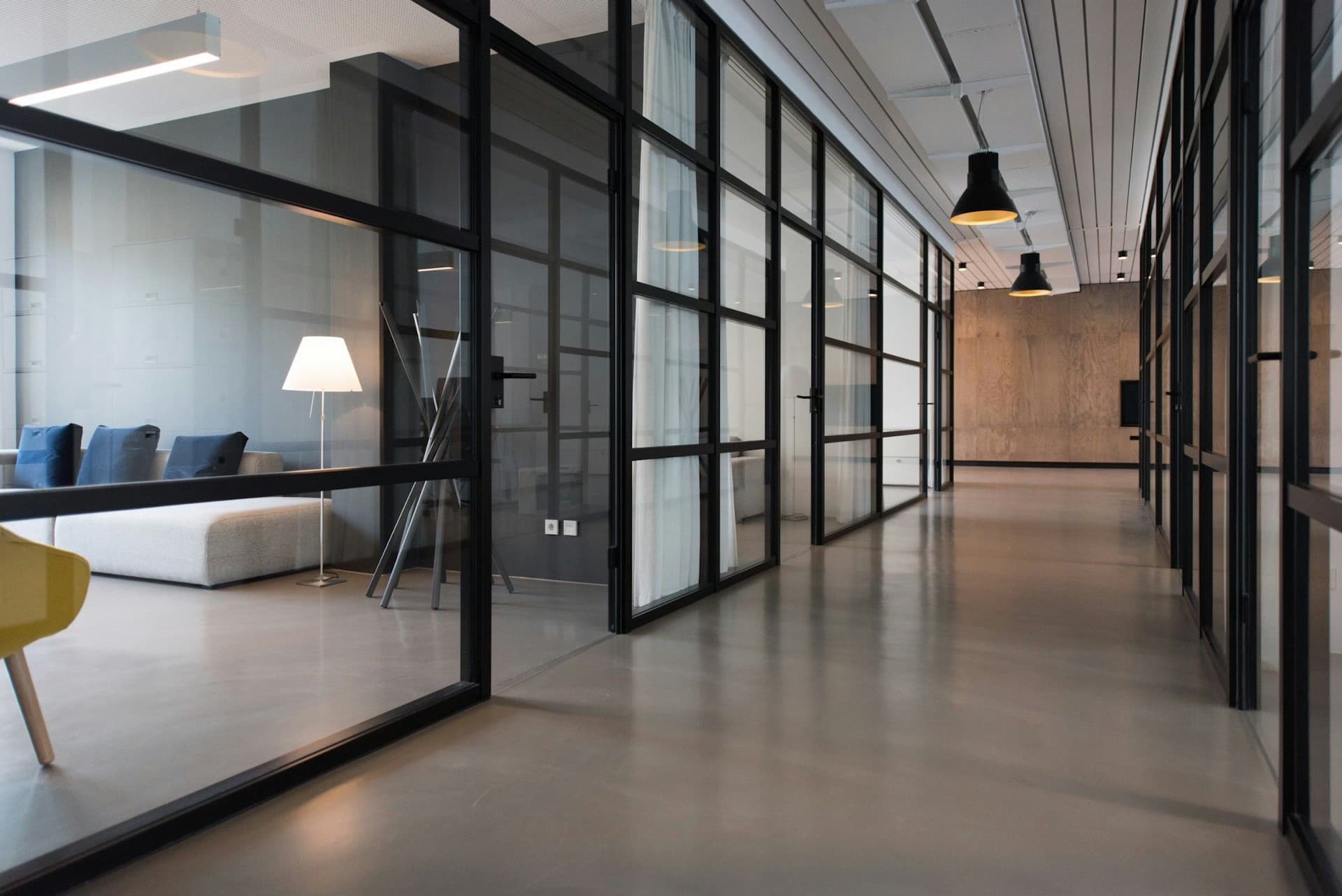 A bright, modern office corridor with glass-walled meeting rooms.