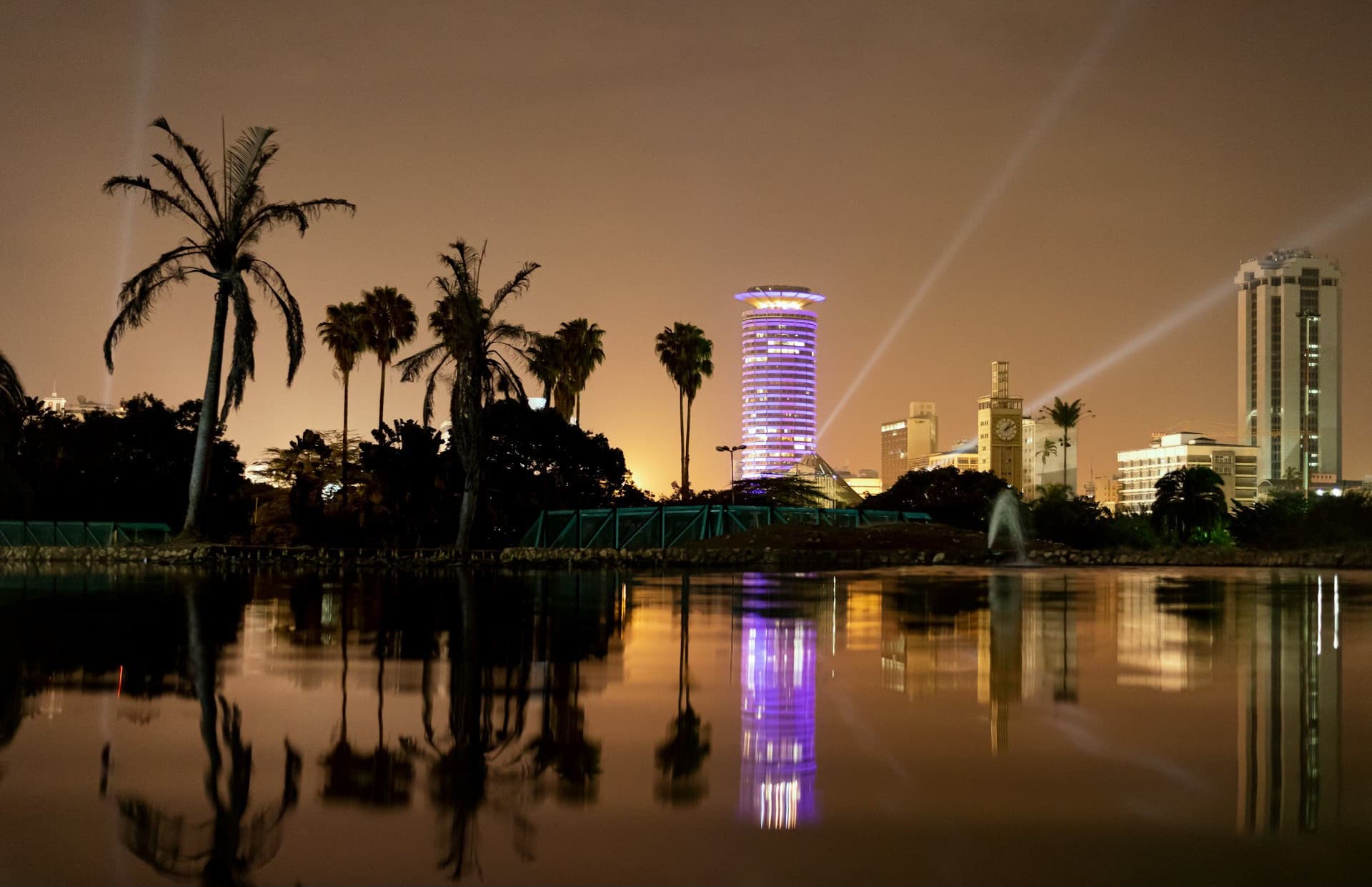 The Nairobi city skyline at dusk, reflected in water.